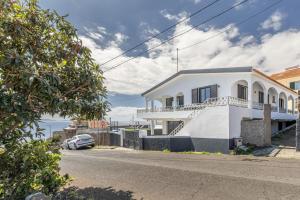 una casa bianca con un'auto parcheggiata davanti di Maylily Seascape Villa a Santa Cruz