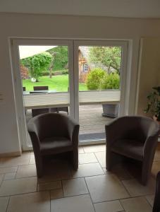 Pokój z 2 krzesłami i przesuwnymi szklanymi drzwiami w obiekcie Haus Ilsegarten w mieście Ilsenburg