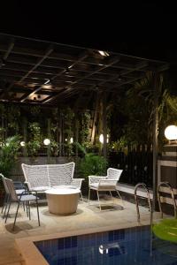un grupo de sillas y una mesa junto a una piscina en Soam Villa - Theatre Room, Plunge Pool & Jacuzzi, en Lonavala