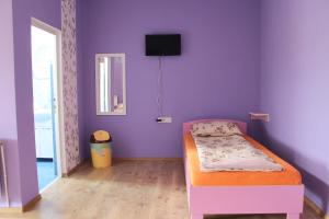 ein Schlafzimmer mit einem Bett in einem lila Zimmer in der Unterkunft SZÁSZ&SZÁSZ PANZIÓ in Gheorgheni