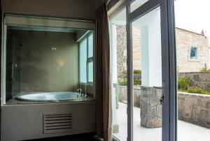 a bathroom with a tub through a sliding glass door at Hotel Puerta del Sol Colca in Yanque