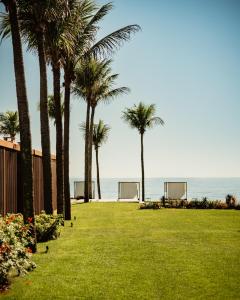 een park met palmbomen en de oceaan op de achtergrond bij A Concept Hotel & Spa in Búzios