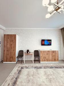 a living room with two chairs and a table and a tv at Hotel Bereket Karaganda in Karagandy