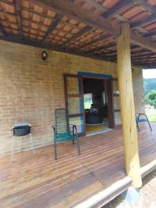 a wooden deck with two chairs and a mirror at Chalé Pedra Chanfrada 03 in Gonçalves +1 photo