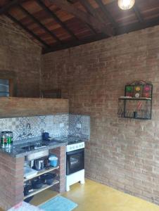 a kitchen with a brick wall and a stove at Chalé Pedra Chanfrada 03 in Gonçalves