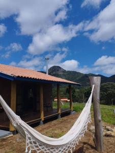 a hammock in front of a house with mountains in the background at Chalé Pedra Chanfrada 03 in Gonçalves
