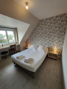 a bedroom with a white bed with a patterned wall at Hôtel Restaurant La Voile Bleue in Erdeven