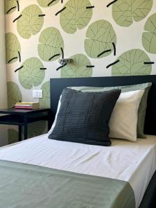 a bedroom with a bed with a wall with green leaves at Appartamenti In Villa Polluce in Fontane Bianche