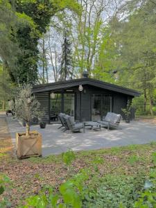 een zwarte cabine met stoelen en een patio bij The Four Oaks House in Garderen