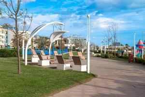 une rangée de bancs dans un parc avec une aire de jeux dans l'établissement Hotel Avana, à Riccione