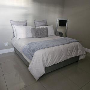 um quarto com uma cama grande com lençóis brancos e almofadas em Duke & Dutchess em Cidade do Cabo