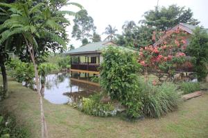 una casa en un jardín junto a un cuerpo de agua en LANDBOW GREEN VILLAGE Homestay Trekking & Village Tour en Bukit Lawang
