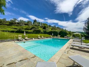 - une piscine dans une cour avec des chaises et un ciel bleu dans l'établissement La Ferriera Exclusive Resort - Pool & Waterfall, à Loro Ciuffenna