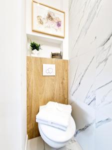 Łazienka z białą toaletą i marmurowymi ścianami w obiekcie J&W Apartments Grójecka Glam Flat w Warszawie
