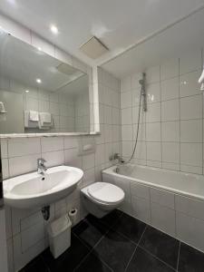 uma casa de banho com um lavatório, um WC e um espelho. em Hotel Monopol City Centre em Dusseldorf