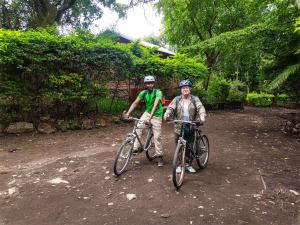 two men standing with their bikes on a dirt road at Shamba Hostel in Usa River