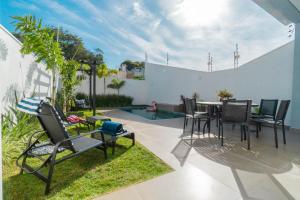 Un patio con mesa y sillas y una piscina. en Kamabre Luxury Villas, en Foz do Iguaçu