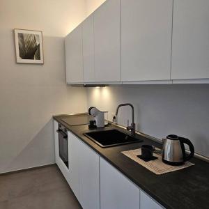 Una cocina con gabinetes blancos, un fregadero y una estufa. en La Casetta, en Alba