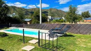 einen Pool mit zwei Stühlen neben einem Zaun in der Unterkunft La Calma in Villa General Belgrano