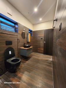 ein Badezimmer mit einer schwarzen Toilette und einem Waschbecken in der Unterkunft Mickey Homestay in Thekkady
