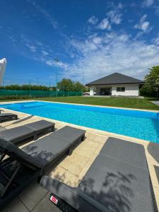 a swimming pool with two chaise lounges next to a house at LaHuzur in Săftica
