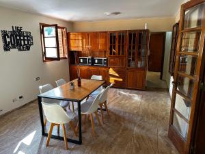 uma cozinha com uma mesa de madeira e cadeiras brancas em Cervantes - Casa de huespedes - Chacras de Coria em Ciudad Lujan de Cuyo
