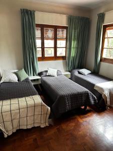 um quarto com 2 camas e cortinas verdes em Cervantes - Casa de huespedes - Chacras de Coria em Ciudad Lujan de Cuyo