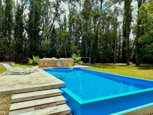 a swimming pool in a yard next to a field at Cervantes - Casa de huespedes - Chacras de Coria in Ciudad Lujan de Cuyo