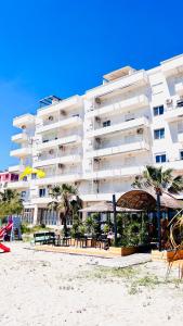 - un grand bâtiment blanc sur la plage avec des tables et des chaises dans l'établissement Soleil Apartment with sunbed & umbrella, à Vlorë