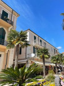 a building with palm trees in front of it at Brezza Marina in Diano Marina