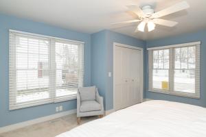 - une chambre avec des murs bleus, un ventilateur de plafond et une chaise dans l'établissement Tranquility Beach House - Beautiful cape cod style home just a short walk to Oak Street beach access, à South Haven