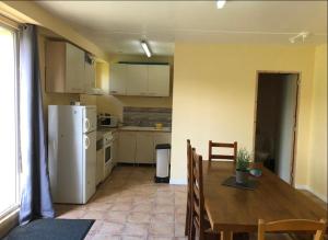 a kitchen with a table and a white refrigerator at Studio à la campagne in Hanvoile