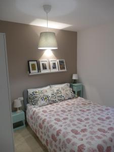 ein Schlafzimmer mit einem Bett und einer Lampe und Bildern an der Wand in der Unterkunft Casita con encanto en Baiona a lado de las playas de Santa Marta y Ladeira in Baiona