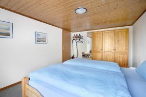 a bedroom with a blue bed and a wooden ceiling at Ferienwohnung Kilian in Oersberg