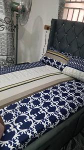 uma cama com lençóis azuis e brancos e uma ventoinha em Captivating 1-Bed Apartment in Oregun Lagos em Lagos