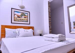 ein Schlafzimmer mit einem weißen Bett und Handtüchern darauf in der Unterkunft HOSPEDAJE LA MERCED in Juanjuí