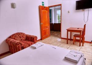Zimmer mit einem Bett, einem Stuhl und einem Tisch in der Unterkunft HOSPEDAJE LA MERCED in Juanjuí