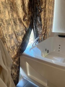une baignoire avec rideau à côté d'une fenêtre dans l'établissement FEMME noir LUXURy spa EXPERIENCE, à San Nicola La Strada