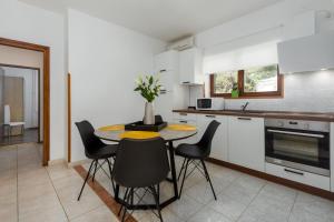 uma cozinha com mesa e cadeiras num quarto em Silvia big private garden em Funtana