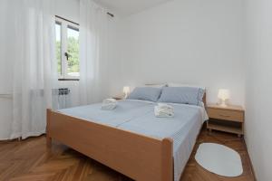 um quarto branco com uma cama e uma janela em Silvia big private garden em Funtana