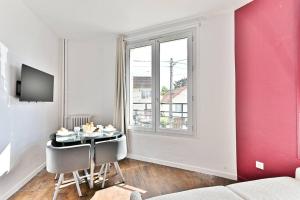 a room with a table and chairs and a window at Appartement Rose Moderne Proche de la capitale in Gagny