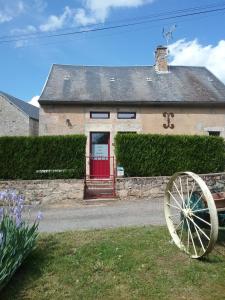 a house with a red door and a wooden wheel at Les petites Fourches in Saint-Brisson