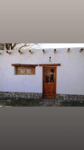 a white building with a wooden door and a window at El Paraiso in Tinogasta