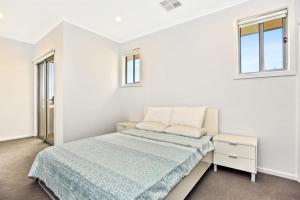 a white bedroom with a bed and two windows at Avaya Sellicks Beachfront Getaway- Wifi in Sellicks Beach