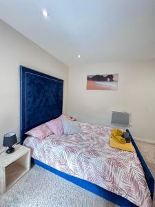 een slaapkamer met een bed met een blauw hoofdeinde en een laptop bij Excelsior Holiday Apartments Swansea- 2 bedroom includes Free Parking in Swansea
