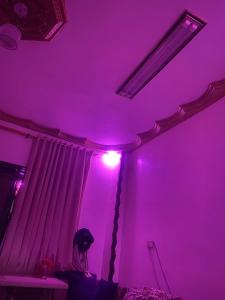 艾斯尤特的住宿－Cozy Private Apartment，坐在紫色房间床上的女人