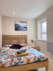 ein Schlafzimmer mit einem Bett mit einer Decke und einem Fenster in der Unterkunft Excelsior Holiday Apartments Swansea- 2 bedroom includes Free Parking in Swansea