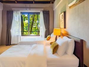two beds in a room with a window at Perch El Nido's Seaview Villas Marimegmeg Beach in El Nido