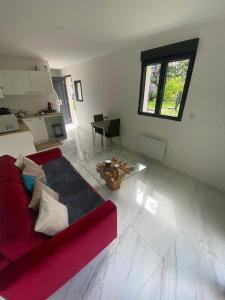 ein Wohnzimmer mit einem roten Sofa und einem Tisch in der Unterkunft Tiny House DALIA Jardin & forêt 10 min de la gare in Dammarie-les-Lys