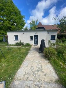 ein weißes Haus mit einem Stuhl davor in der Unterkunft Tiny House DALIA Jardin & forêt 10 min de la gare in Dammarie-les-Lys